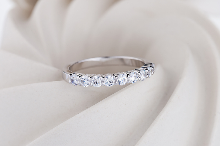 Female pave diamonds wedding ring on white spiral background. Engagement ring with gemestones