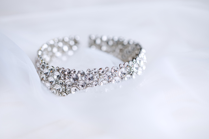 Bridal necklace with rhinestones close-up on a white organza. Wedding womens jewelry. Horizontal photo in light colors.
