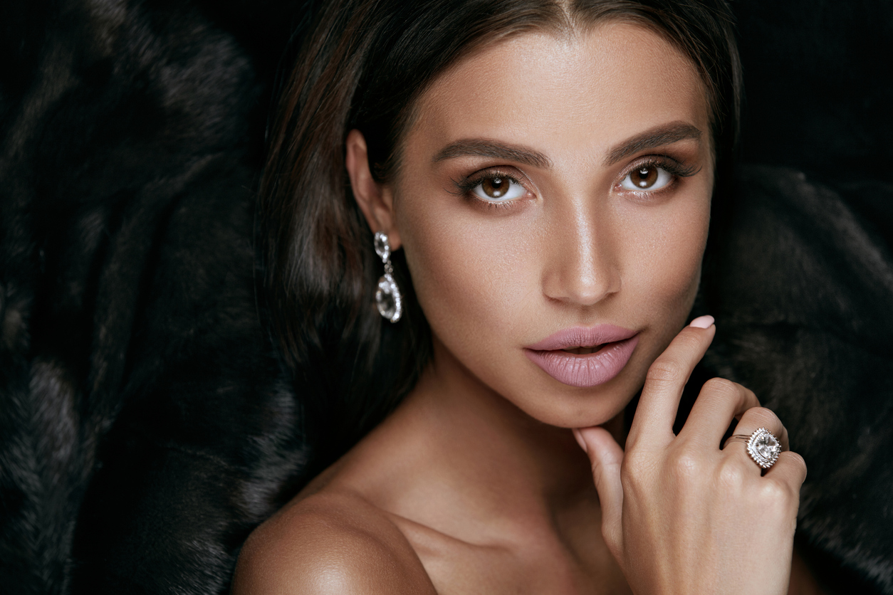 Beauty Makeup. Gorgeous Woman Face With Jewelry. Sexy Young Female In Luxury Black Fur Coat With Beautiful Facial Makeup Wearing Gold Diamond Earrings And Ring. Fashion Look. High Quality Image.